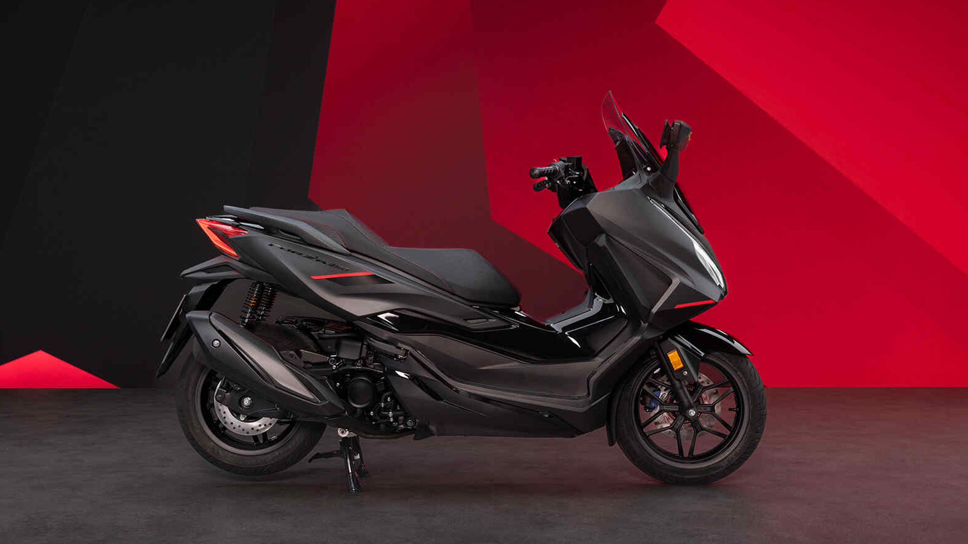 Honda Forza 350 garé devant un bâtiment moderne, vue de profil