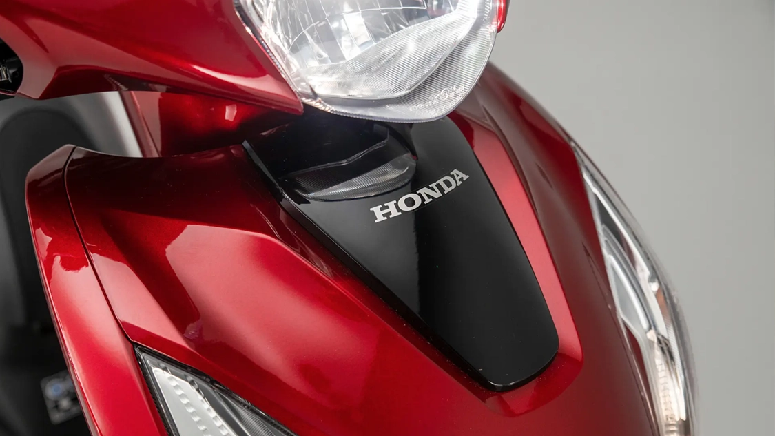 Honda Vision 110 garé devant un café